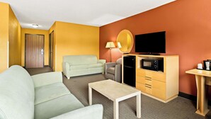 A hotel room with a sofa, a small table, a TV, a microwave, a lamp, and a desk. - Best Western Paducah Inn (Paducah)