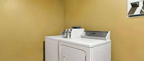 A laundry room with a front-loading washer and dryer, a wall-mounted dryer, and a tiled floor.