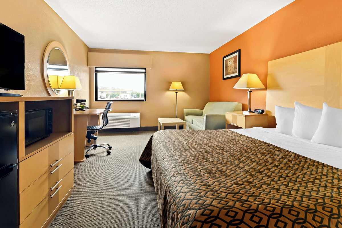 A hotel room with a bed, desk, chair, TV, and a window.