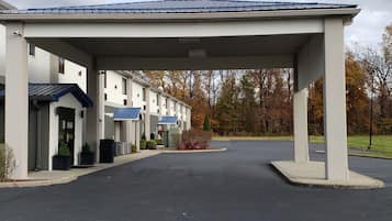 A hotel with a covered entrance, multiple rooms, and a parking area.