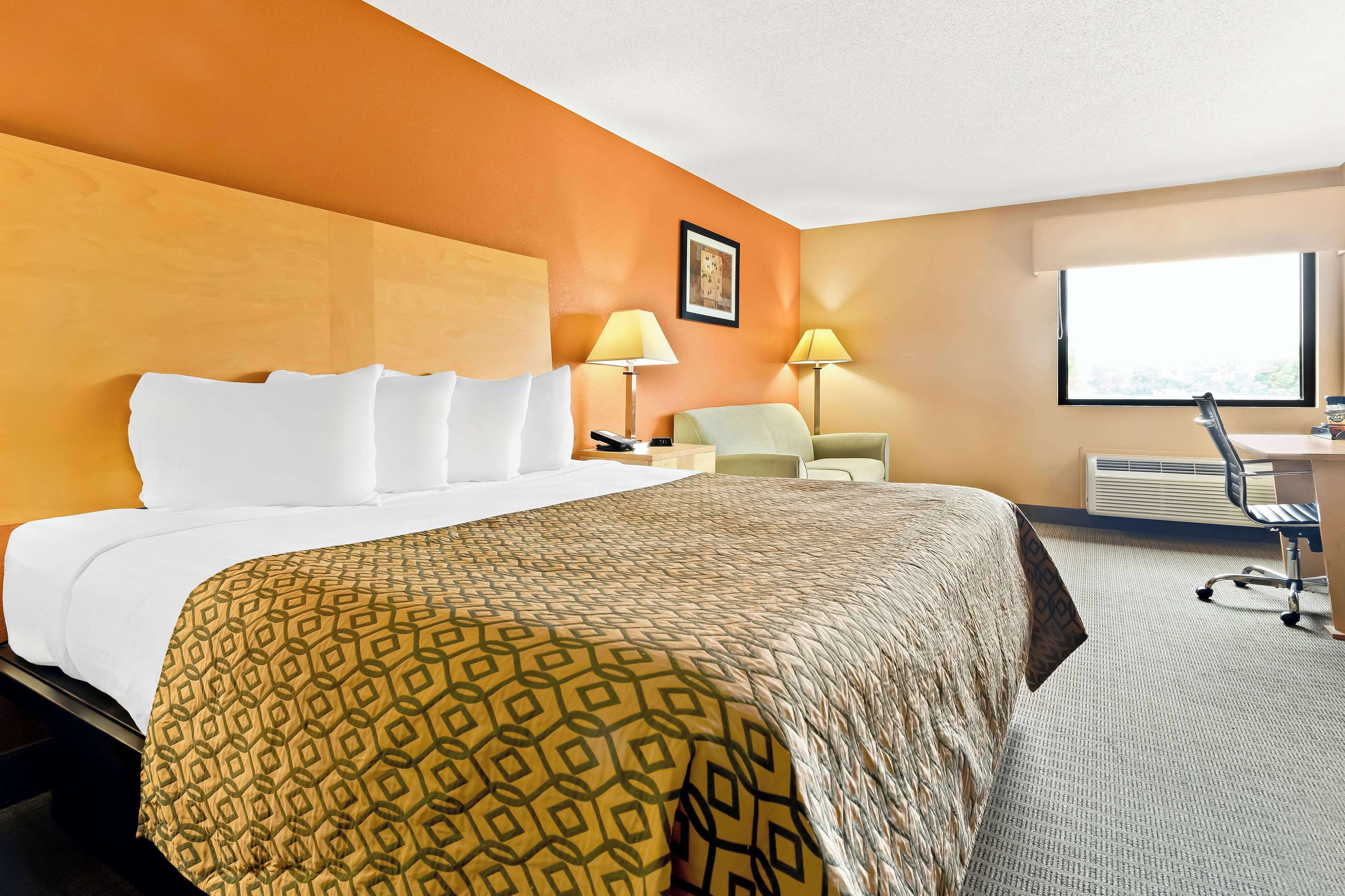 A hotel room with a large bed, two bedside lamps, a desk, and a chair.