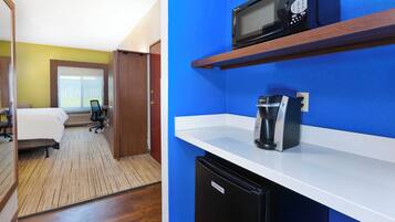 Habitación de hotel con cama, escritorio, silla y kitchenette.