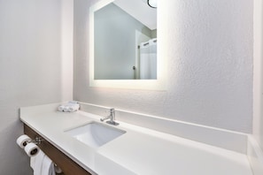 A bathroom with a white sink, a mirror, and a towel rack with towels.