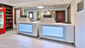 A reception area with two counters, a Coca-Cola refrigerator, and a mirror.