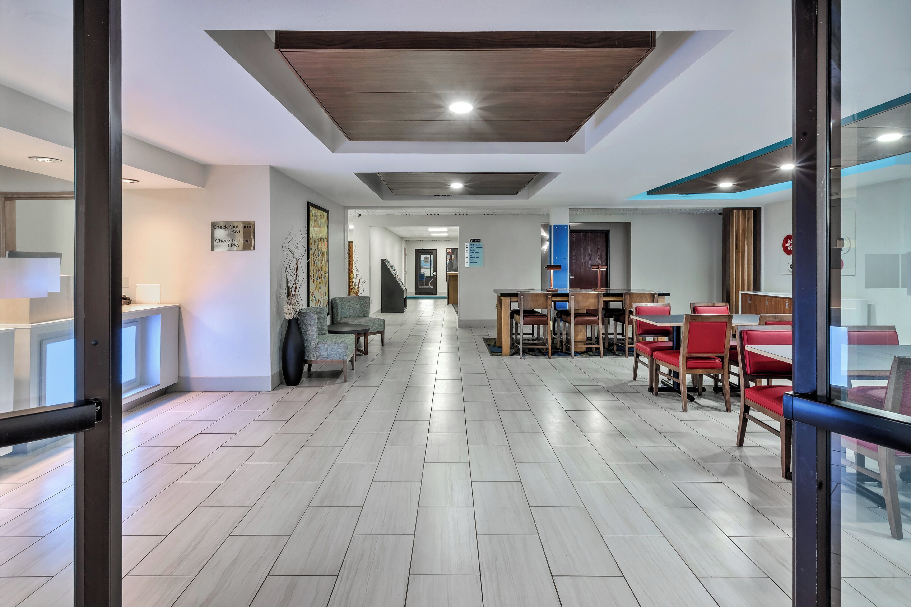 Un hall d’hôtel au design moderne, comprenant un comptoir d’enregistrement, un espace salon et un escalier menant aux autres étages.