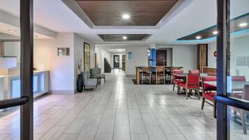 Un hall d’hôtel au design moderne, comprenant un comptoir d’enregistrement, un espace salon et un escalier menant aux autres étages.