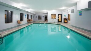 A swimming pool with a tiled deck, surrounded by white walls and doors. - Holiday Inn Express & Suites Three Rivers by IHG (Three Rivers)