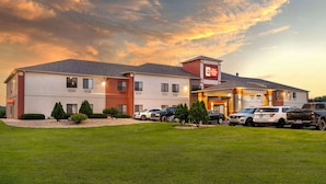 Un hotel con aparcamiento, varios vehículos y un césped bien cuidado.