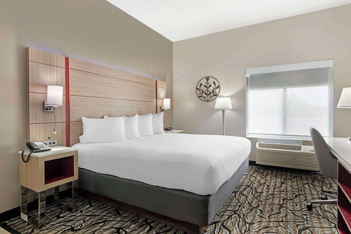 Ein Hotelzimmer mit einem großen Bett, Nachttischen, einem Schreibtisch und einem Fenster.