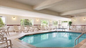 Una piscina interior con sillones de descanso y suelo de baldosas.