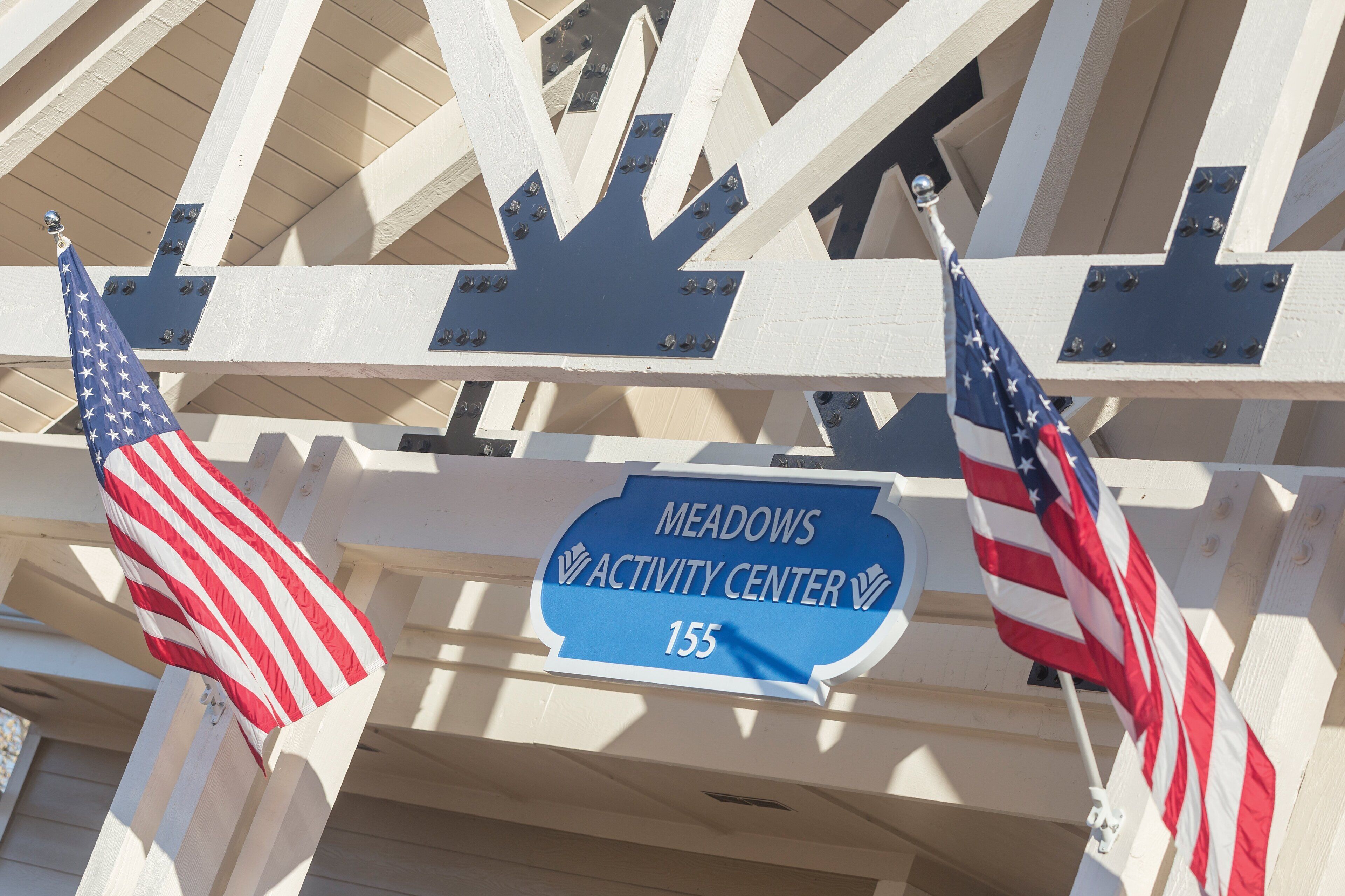 A sign for Meadows Activity Center with two American flags.