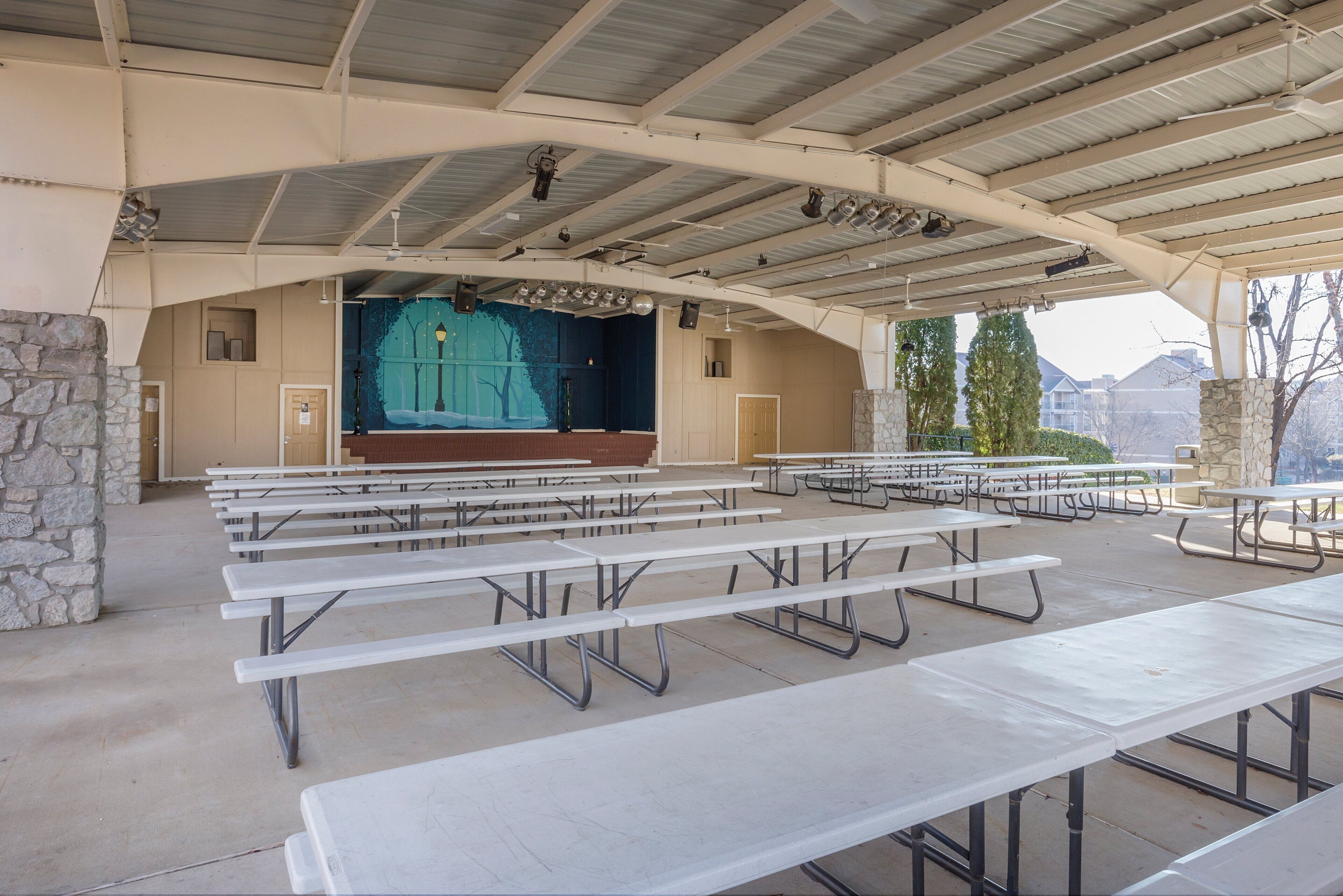 An outdoor amphitheater with picnic tables and a stage.