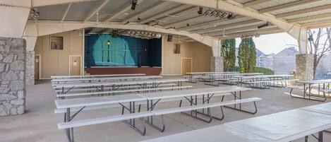 An outdoor amphitheater with picnic tables and a stage.