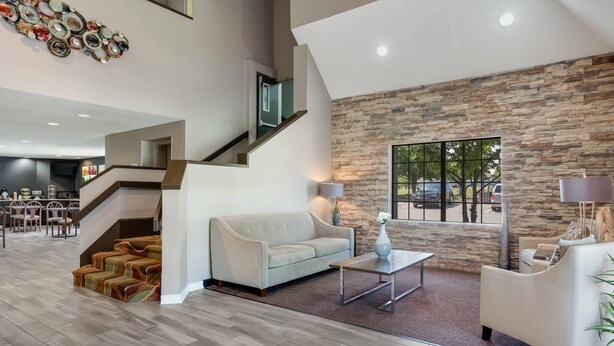 Amplia sala de estar con una escalera moderna, una pared de acento de piedra y vistas al exterior.