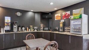 Una cocina moderna con comedor, equipada con cafetera, microondas y refrigerador.