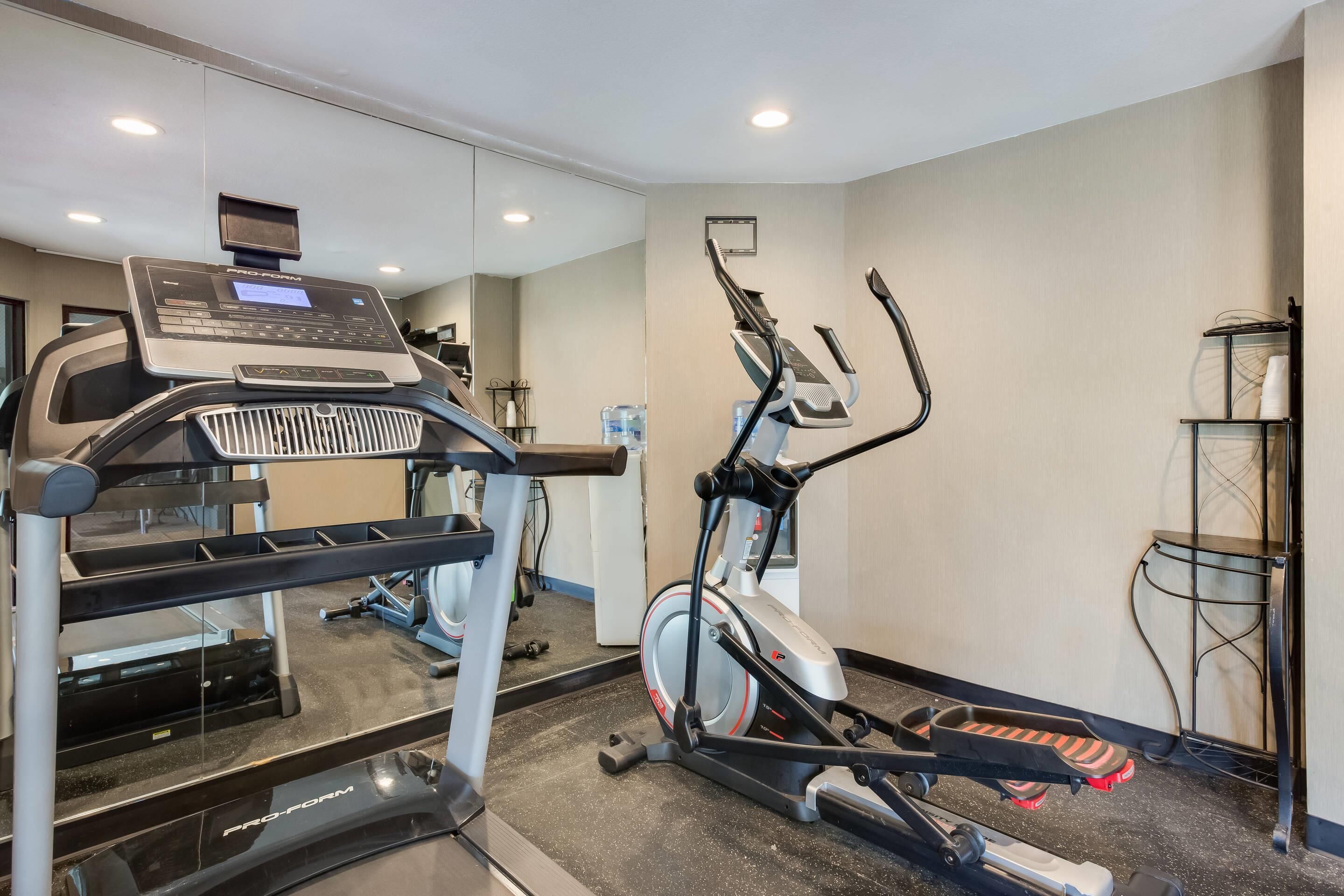 A gym with cardio equipment including a treadmill, elliptical, and stationary bike.