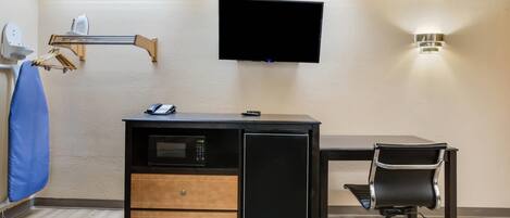 Habitació d'hotel petita amb escriptori, televisió penjada a la paret, microones i frigorífic petit.