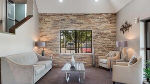 Una sala de estar moderna con una pared de piedra, un ventanal grande y un sofá.