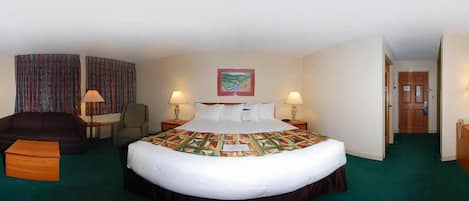 A hotel room with a large bed, two bedside lamps, a chair, a sofa, and a painting on the wall.