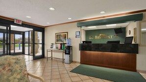 A reception area with a reception desk, a chair, a water dispenser, and a painting on the wall. - Baymont by Wyndham Sullivan (Sullivan)