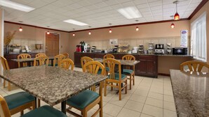 A restaurant with a marble dining table, wooden chairs, and a kitchen area with various appliances. - Baymont by Wyndham Sullivan (Sullivan)