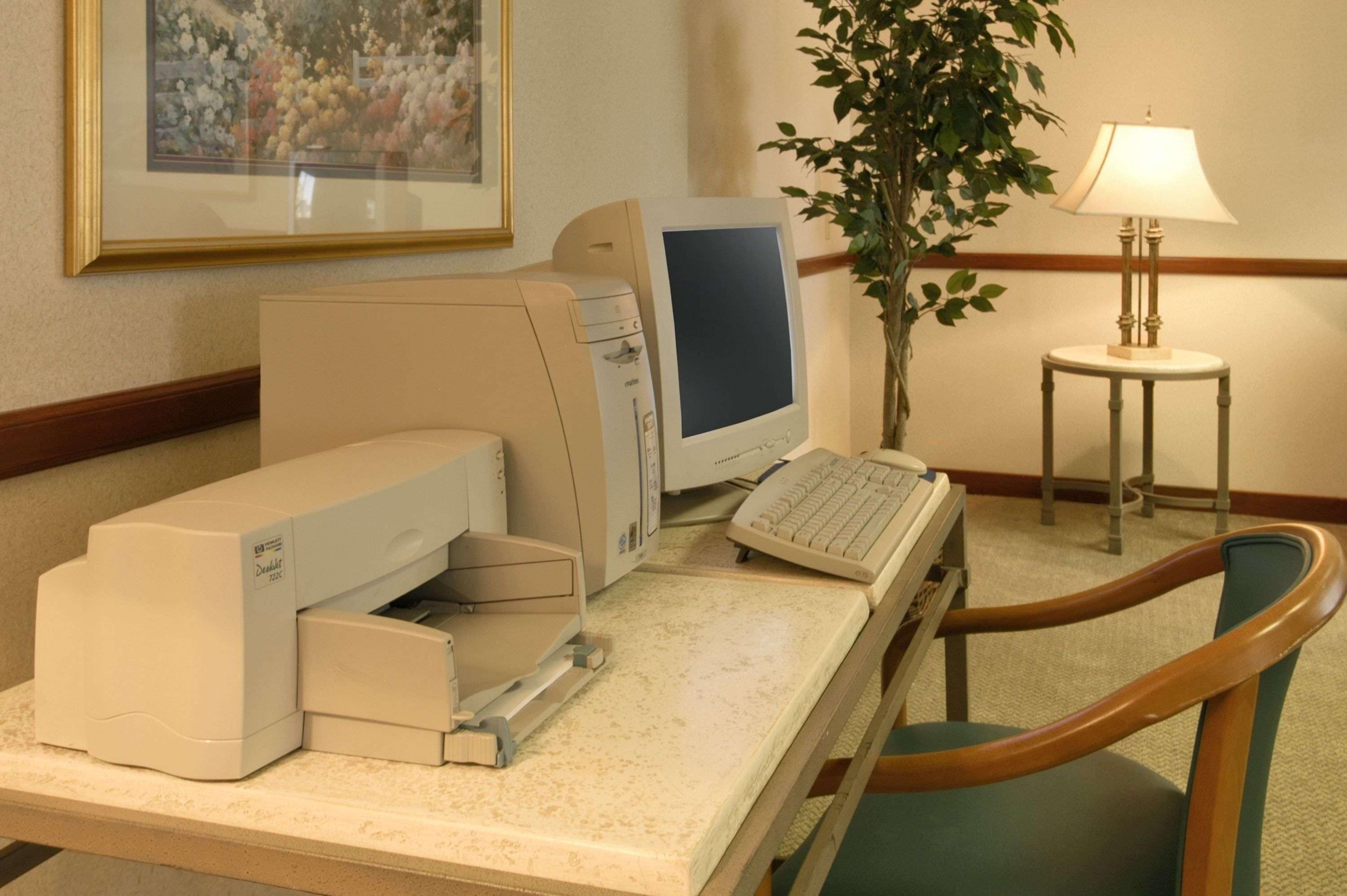 A desk with a desktop computer, a printer, and a lamp.