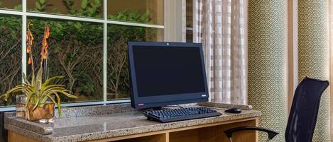 A hotel workspace with a computer, keyboard, and monitor on a granite desk.