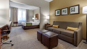Habitación de hotel con cama, sofá, escritorio y una silla. Seis cuadros enmarcados decoran la pared.