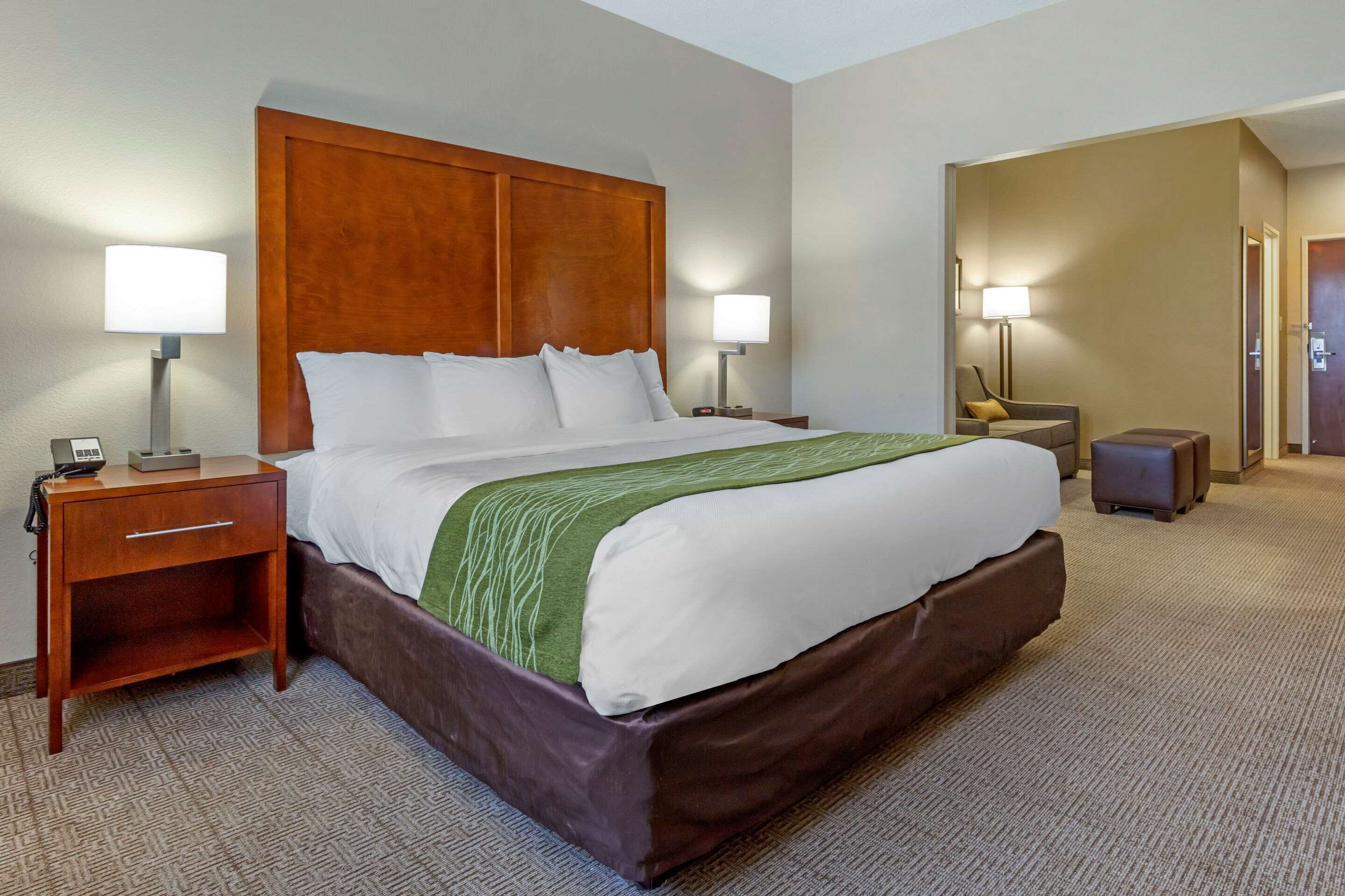 A hotel room with a large bed, two bedside tables, a nightstand, a lamp, and a chair.