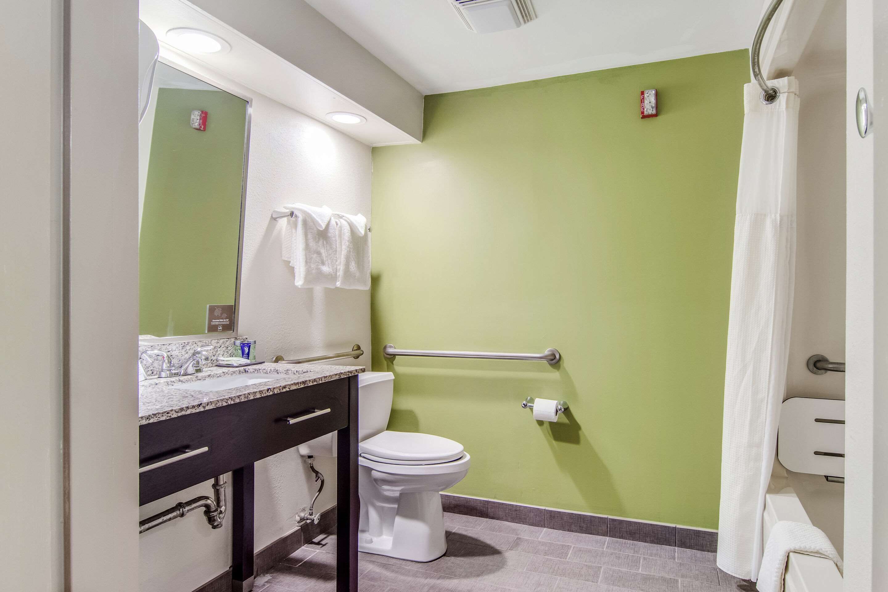 Ein Badezimmer mit grüner Wand, weißer Toilette und einer Marmorarbeitsplatte.