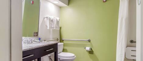 Baño con pared verde, inodoro blanco y encimera de mármol.