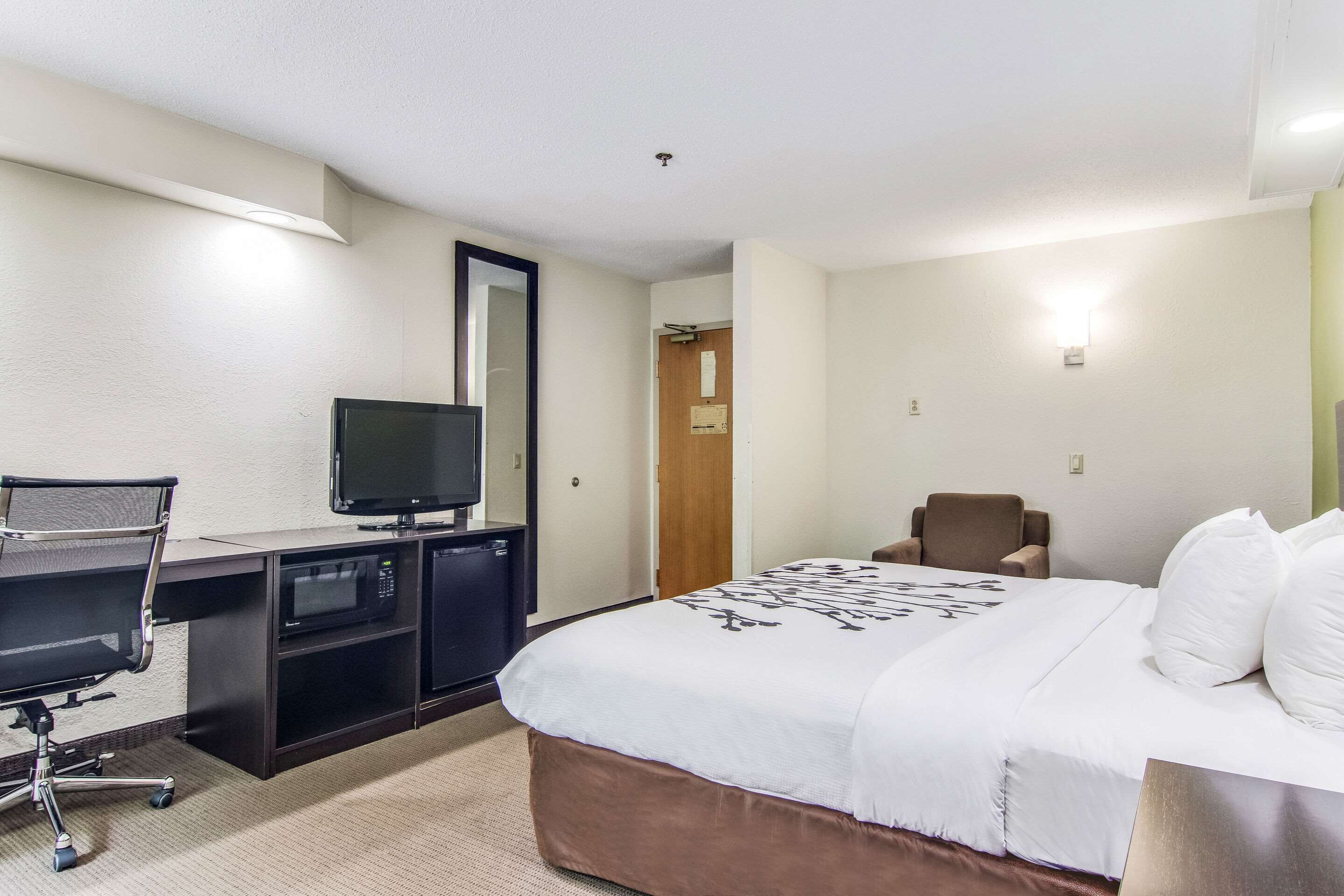 A hotel room with a bed, a desk with a computer, a television, and a chair.