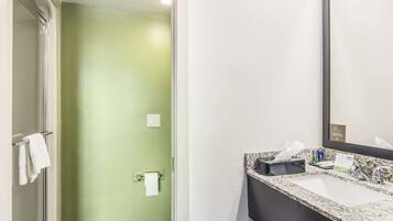 Een badkamer met een groene muur, een wit wastafeltje en een spiegel.