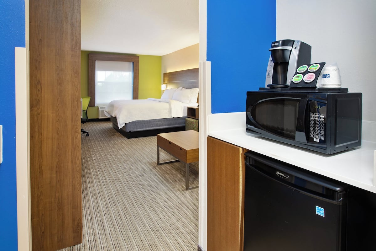 A hotel room with a bed, a desk, a microwave, and a coffee maker.
