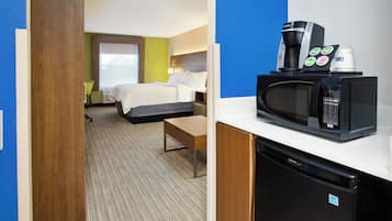 A hotel room with a bed, a desk, a microwave, and a coffee maker.