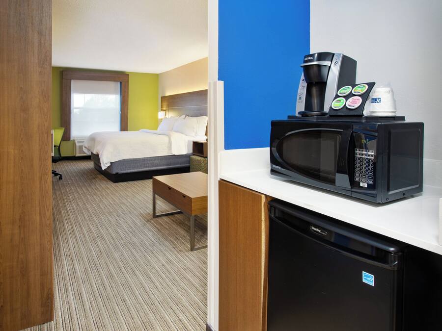 A hotel room with a bed, a desk, a microwave, and a coffee maker.