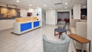 Un vestíbulo moderno con mostrador de recepción, zona de estar y una pequeña kitchenette.
