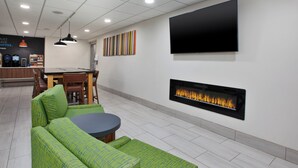 Una sala de estar moderna con un sofá verde, una mesa redonda, un televisor de pantalla plana y una chimenea.