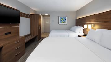 A hotel room with two beds, a TV, a wooden wardrobe, and a framed picture on the wall.