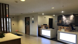 A hotel reception area with a modern design, including a reception desk, a wall-mounted information board, and a visible exit sign. - Holiday Inn Express Mt Vernon by IHG (Mount Vernon)