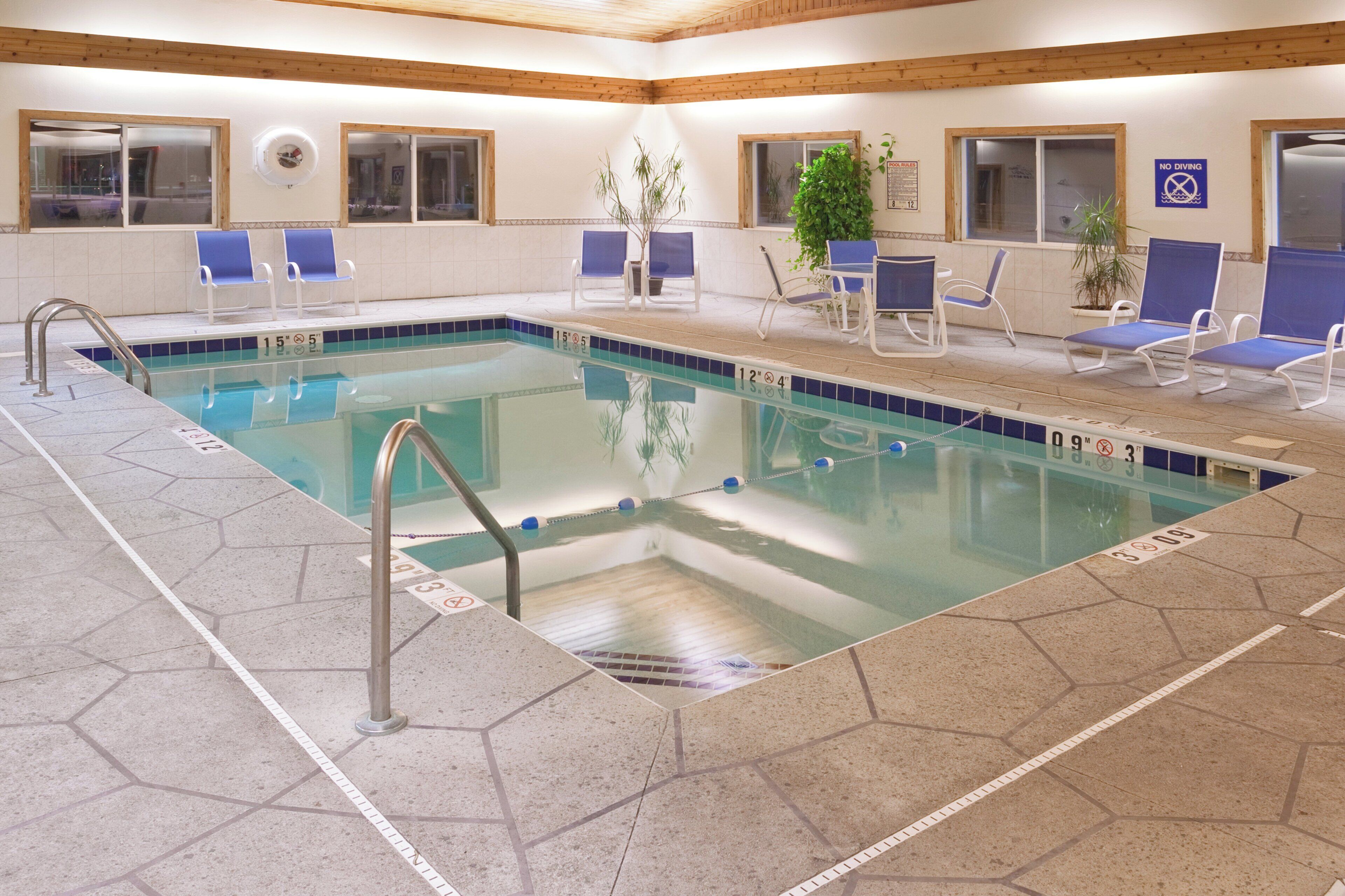 An indoor swimming pool with clear water, marked depth lines, and a tiled floor.