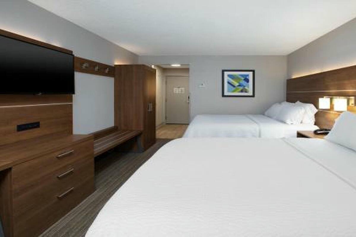 Een hotelkamer met twee bedden, een televisie, een bureau en een schilderij aan de muur.