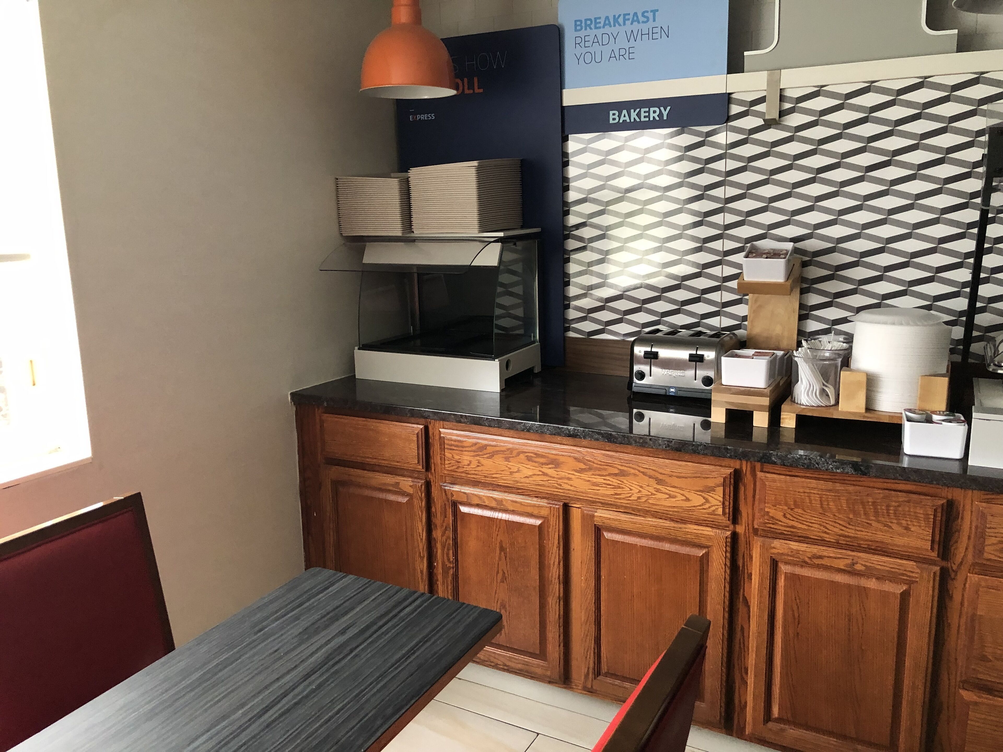 A kitchen with wooden cabinets, a black countertop, a toaster, and a sign indicating a bakery.