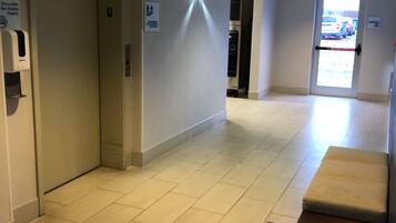 Un pasillo con un banco, un ascensor y una puerta señalizada con 'EXIT'.