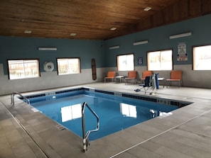 Une piscine intérieure avec des marquages bien visibles, un plafond en bois et plusieurs fenêtres.
