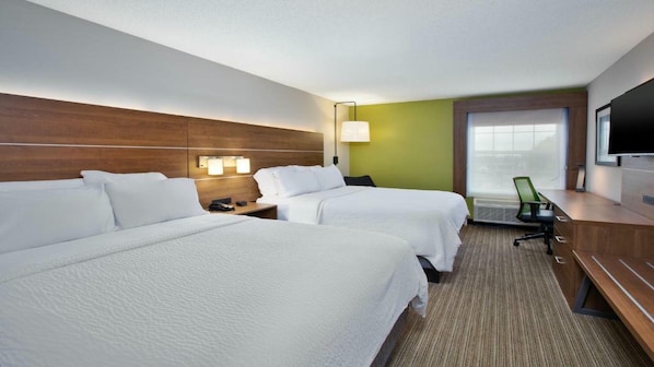 A hotel room with two beds, a desk, a TV, and a window with a view.