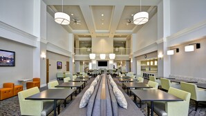 A spacious hotel lobby with multiple seating areas, a central staircase, and a large TV screen. - Homewood Suites by Hilton Hillsboro/Beaverton (Beaverton)
