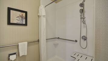 A shower area with a handheld showerhead, a towel rack, and a framed sign on the wall.