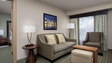 A hotel room with a sofa, a chair, a small table, and a bed.