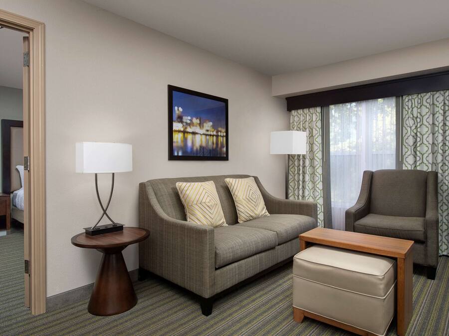 A hotel room with a sofa, a chair, a small table, and a bed.